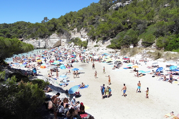 A busy beach during high season in Menorca